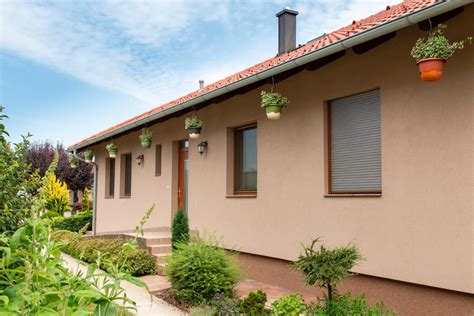 Napfényben álló modern ház ablakain műanyag redőnyökkel